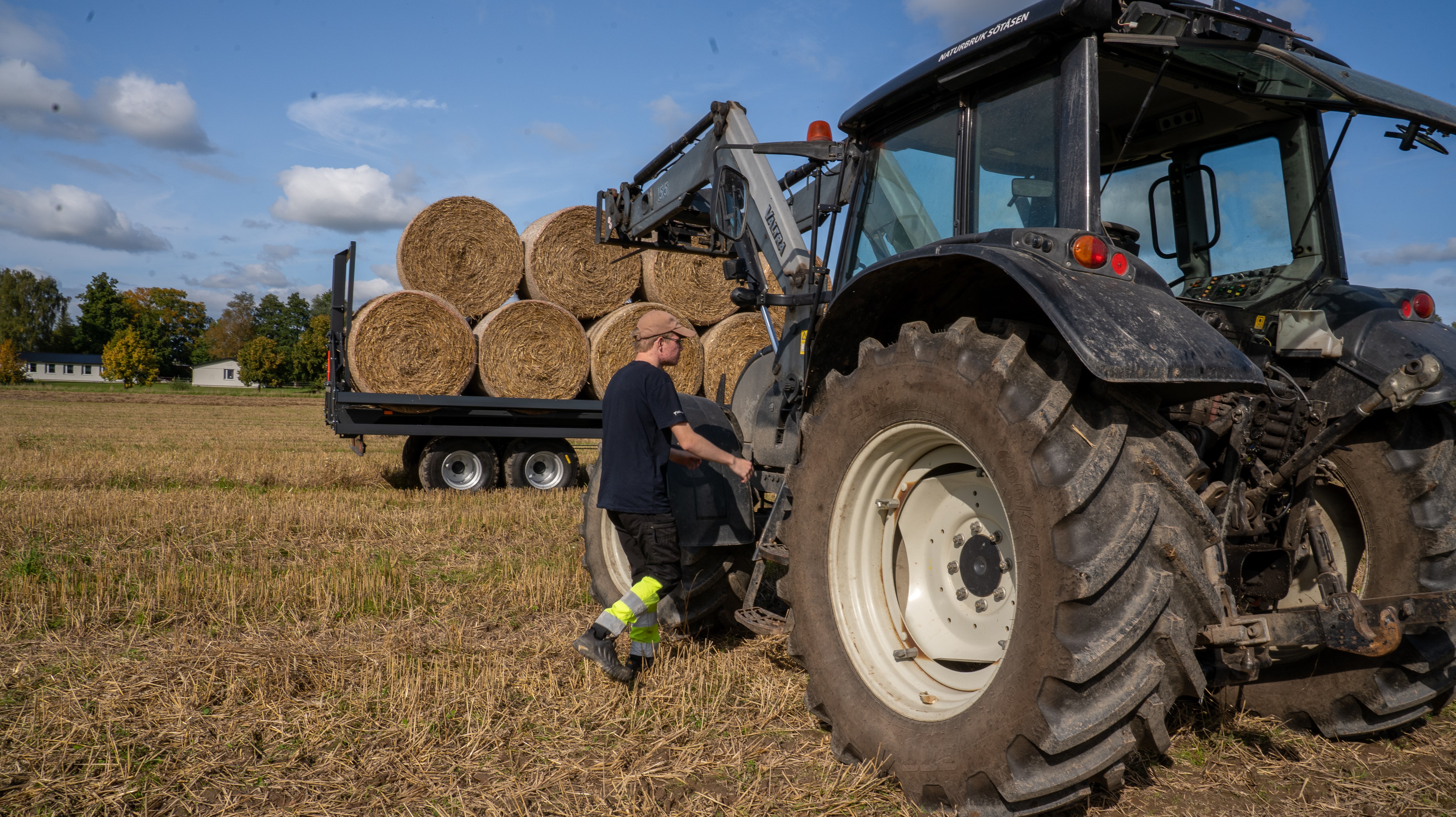 Elev går mot traktor som står parkerad framför balvagn